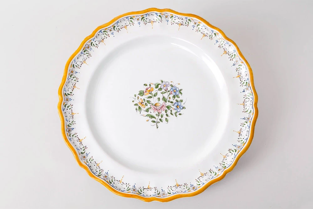 Assiette plate Louis XV avec décor au bouquet polychrome et frise